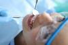 Dentist examining oral cavity of woman patient in clinic using tools closeup
